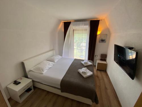 a bedroom with a bed with a window and a television at Vikendica sa bazenom in Višegrad