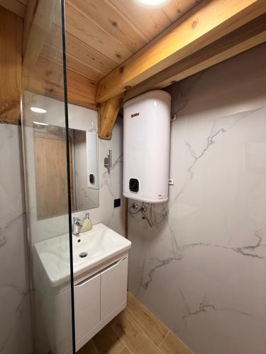 a bathroom with a white sink and a shower at Alvearium Chalets in Žabljak