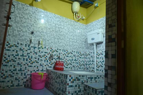 a bathroom with a tiled shower with a pink bucket at Bagan Bilas Homestay in Jhilimili