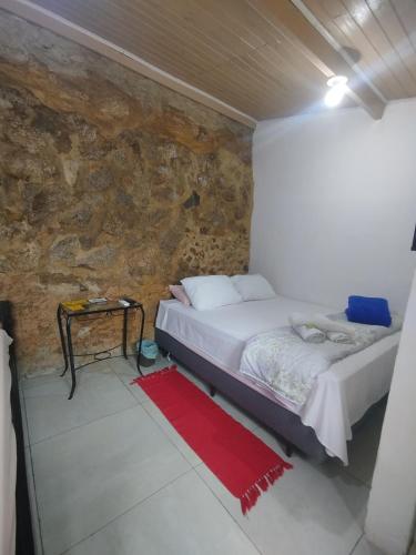 a bedroom with a bed and a stone wall at Casinha Centro histórico in Paraty