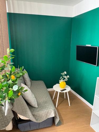 a green living room with a couch and a table at Studio cosy - inspiré de Capri in Bar-le-Duc