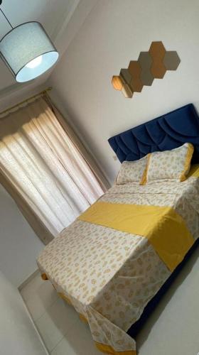a bedroom with a bed with a blue headboard and a window at Appartement mansoria in Mansouria