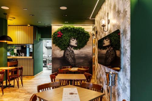 a restaurant with tables and chairs and paintings on the wall at Sloh Hotel & Bar Manila Medellin in Medellín
