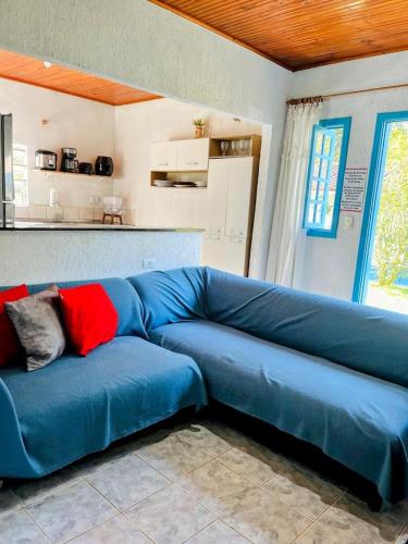 a blue couch in a room with a kitchen at Vila de Casas de Campo Rústica e Aconchegante na Mata Atlântica in Juquitiba