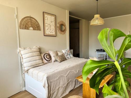 a bedroom with a bed with pillows and a plant at Le Cocon Bohème, appartement chaleureux in Sarrebourg