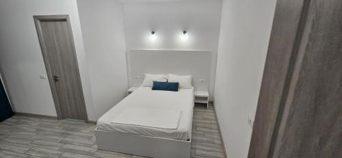 a white room with a bed with a blue pillow on it at Casa Elizé in Schitul
