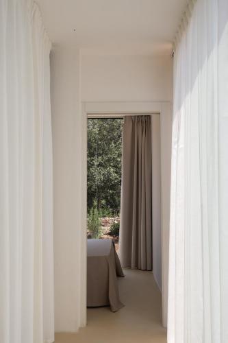 a bedroom with white curtains and a window at Quercia Private Nature Retreat in Maglie
