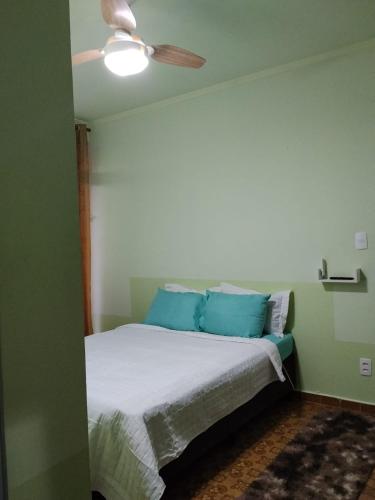 a bedroom with a bed with blue pillows and a ceiling fan at Pousada Essenza lindoía in Águas de Lindoia