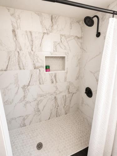 a shower with a white marble wall at The Cozy Corner House in Kissimmee