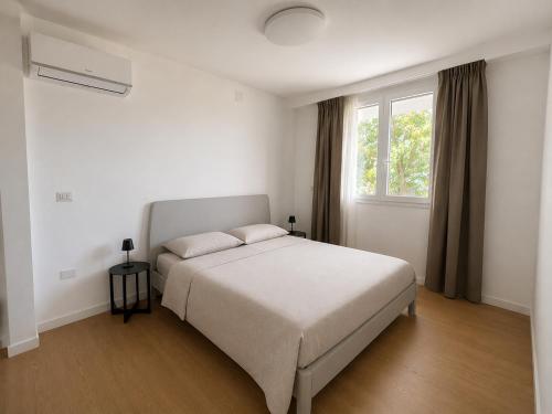 a white bedroom with a bed and a window at Lentamente Domo in San Giovanni