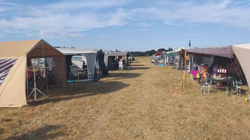 a group of tents and tables and chairs in a field at Slaaptrailer Vierdaagsecamping Malden in Malden