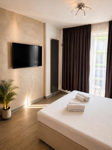 a bedroom with a bed with a flat screen tv on the wall at Alezzi Beach Resort Pool &Spa in Mamaia Sat/Năvodari