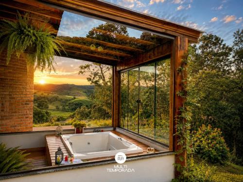 a bath tub in a room with a large window at Chalé Caminho do Sol in Rancho Queimado