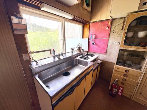 a kitchen with a stainless steel sink and a window at 長峰駅から徒歩3分ゲストハウスオオワニ in Ōwani