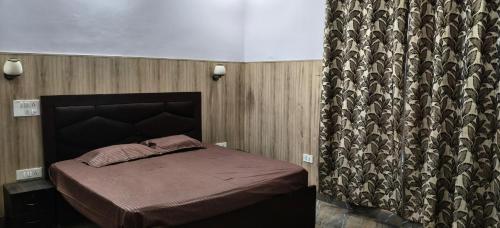 a small bed in a room with a curtain at Hotel Golden Spark in Jewar