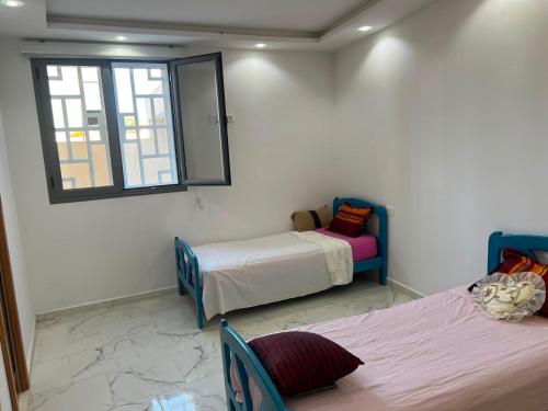 a room with two beds and a mirror and a window at Dar El Baraka in Ghar el Fabs