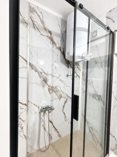 a shower in a bathroom with white marble walls at Apartment Melina in Plužine