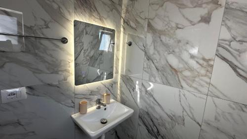 a white bathroom with a sink and a mirror at Vila Roan in Vlorë