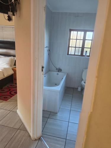 a bathroom with a tub and a toilet and a window at Southernstar 10 st Davids road in Arcadia
