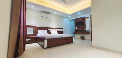 a bedroom with a bed with white sheets and a television at hotel celebrations in Jāmb