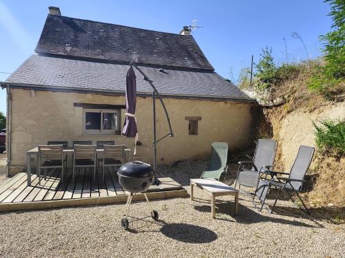 a house with a table and chairs and an umbrella at Gîte les Huttières in Cravant-les-Coteaux