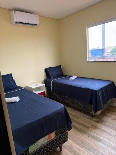 two beds in a room with a window at Casa da Lu in Barreirinhas