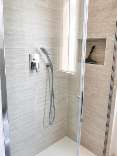 a shower with a glass door with a shower head at Solution Timone - Appartamento al mare in Punta Marina