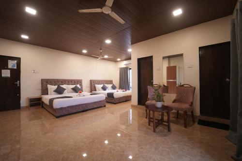 a hotel room with two beds and a table and chairs at Nature's Glory Resort in Panchgani