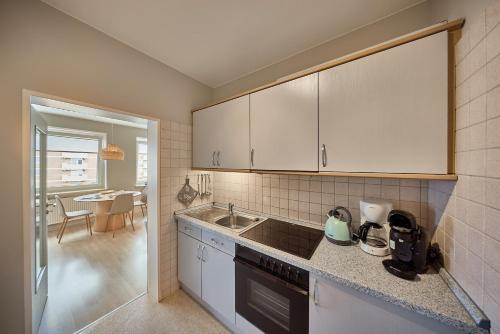 a kitchen with white cabinets and a sink at Haus Schildt, FeWo 5 in Duhnen