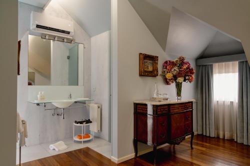 a bathroom with a sink and a vase of flowers at Estrepão House in Moreira de Conegos