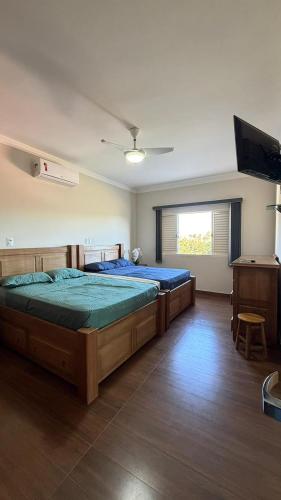 a bedroom with two beds and a flat screen tv at Refúgio com Piscina e Vista Deslumbrante in Caconde