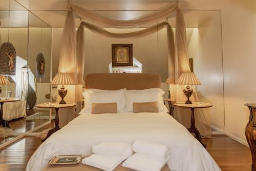 a bedroom with a large white bed with two lamps at Estrepão House in Moreira de Conegos