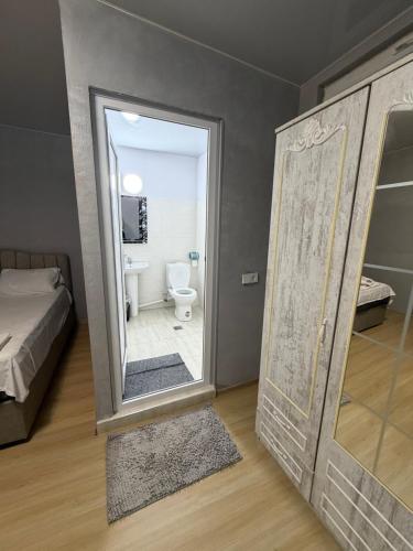 ein Badezimmer mit Spiegel und Toilette in einem Zimmer in der Unterkunft Rezo's Ranch in Samtredia