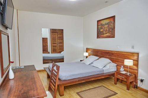 a bedroom with a bed with a wooden headboard at Tripolitsa in Antananarivo