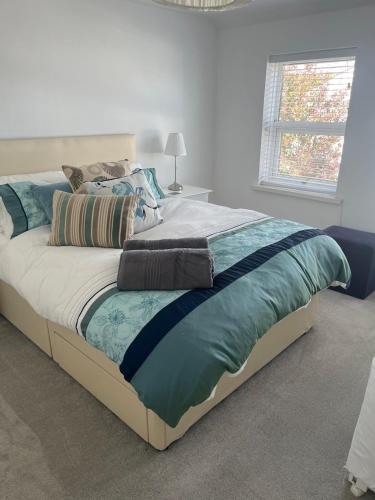 a large bed in a bedroom with a white wall at Coastal Charm Seaside House in Moelfre