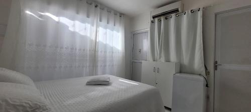 a white bedroom with a bed and a window at Pousada Girassol Genipabu in Extremóz