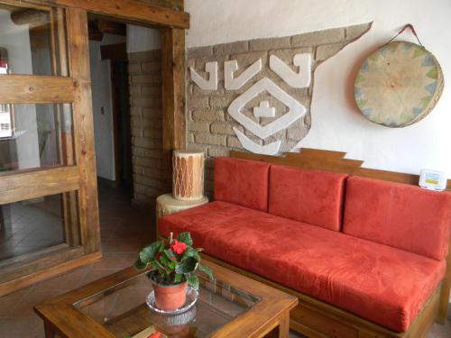 a red couch in a living room with a table at La Troje de Adobe in Creel