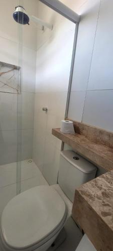 a white bathroom with a toilet and a shower at Pousada Girassol Genipabu in Extremóz