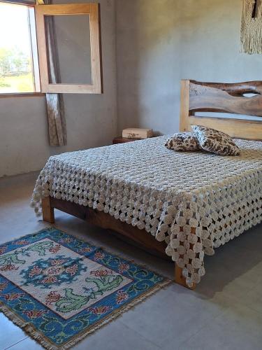 a bedroom with a bed in a room with rugs at Chalé Araucárias-Recanto dos pássaros in Cambuí