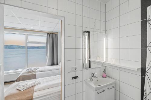 a bedroom with a bed and a sink and a window at Hotel West in Patreksfjörður
