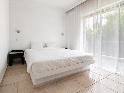 a white bedroom with a bed and a window at Ioli Beach in Skala Fourkas