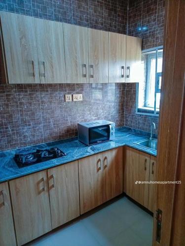a kitchen with wooden cabinets and a microwave at Amnu Homes Apartment in Ilorin