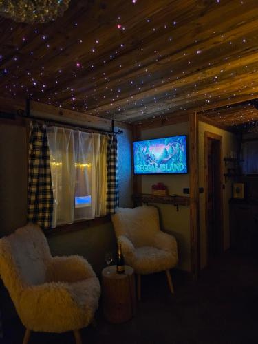 a living room with two chairs and a flat screen tv at Chatka Bystrá jacuzzi,stars,river in Bystrá