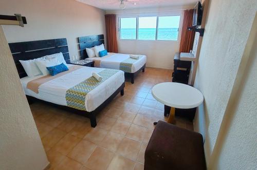 a hotel room with two beds and a table at Hacienda Morelos Beachfront Hotel in Puerto Morelos