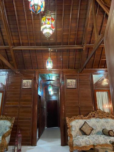 a living room with wooden walls and a ceiling with lights at شالية الكوخ in Salalah