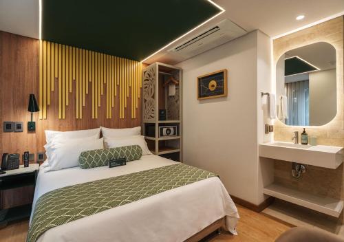 a bedroom with a large bed and a sink at Sloh Hotel & Bar Manila Medellin in Medellín