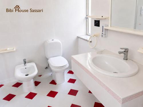 a white bathroom with a toilet and a sink at Bibi House in Sassari