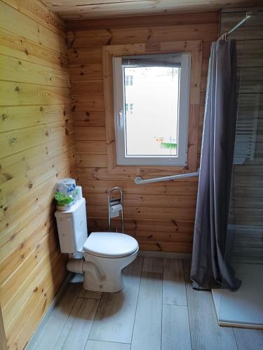 a wooden bathroom with a toilet and a window at Le chalet d'Empeytepas in Céaux-dʼAllègre