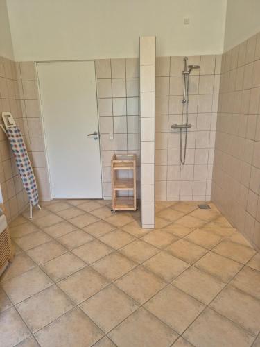 a bathroom with a shower and a tiled floor at Fredfyldt skovbolig med udespa in Rødding