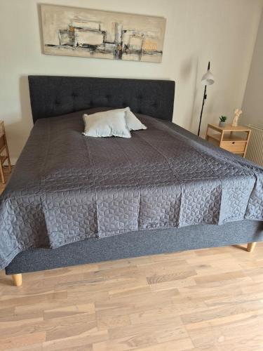 a large bed with a gray comforter in a bedroom at Fredfyldt skovbolig med udespa in Rødding